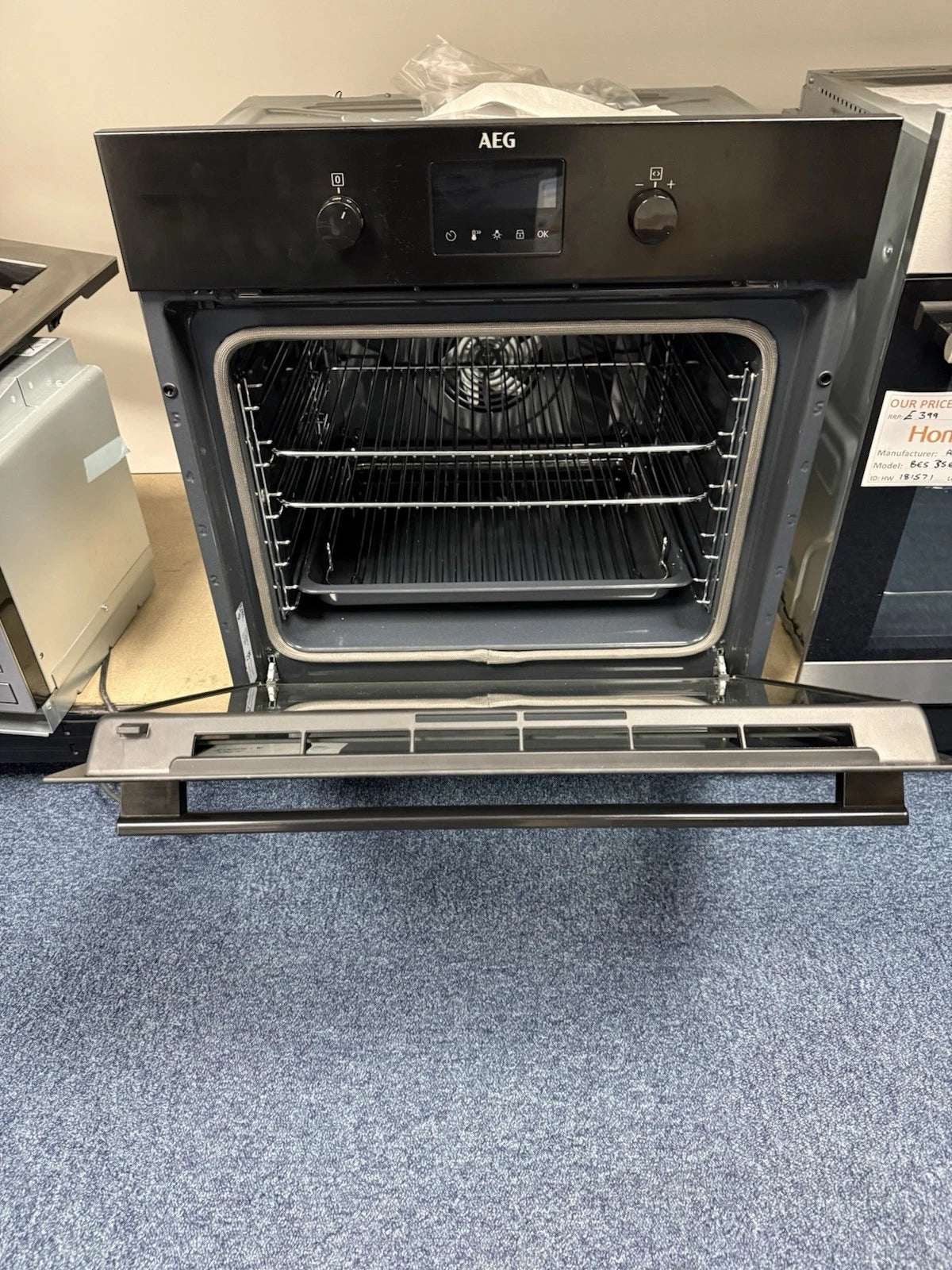 AEG BPK355061B (20) Electric Built-In Single Oven with Pyrolytic Self Cleaning in Black - A+ Rated from HomeWise Appliances. Shop photo of oven on show stand with the door open showing shelves and tray in cavity.