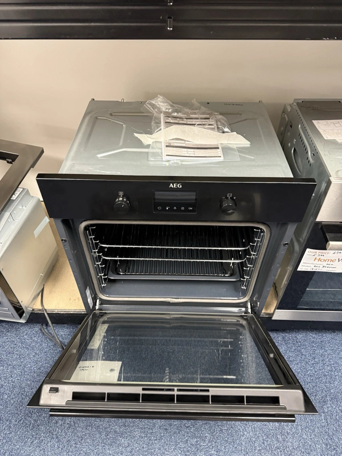 AEG BPK355061B (20) Electric Built-In Single Oven with Pyrolytic Self Cleaning in Black - A+ Rated from HomeWise Appliances. Shop photo of oven on show stand with the door open showing shelves and tray in cavity from above.