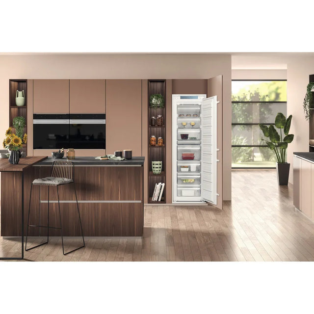 Hotpoint HTSD18F013H1 209 Litre Tall Built-In Freezer with No Frost - E Rated from HomeWise Appliances. Stock photo of the freezer with door open in a kitchen environment.
