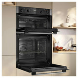 Neff N50 U1ACE2AN3B Built-in Electric Double Oven in Stainless Steel - A/B Rated by HomeWise Appliances. Stock photo showing oven in a kitchen setting with the doors open.