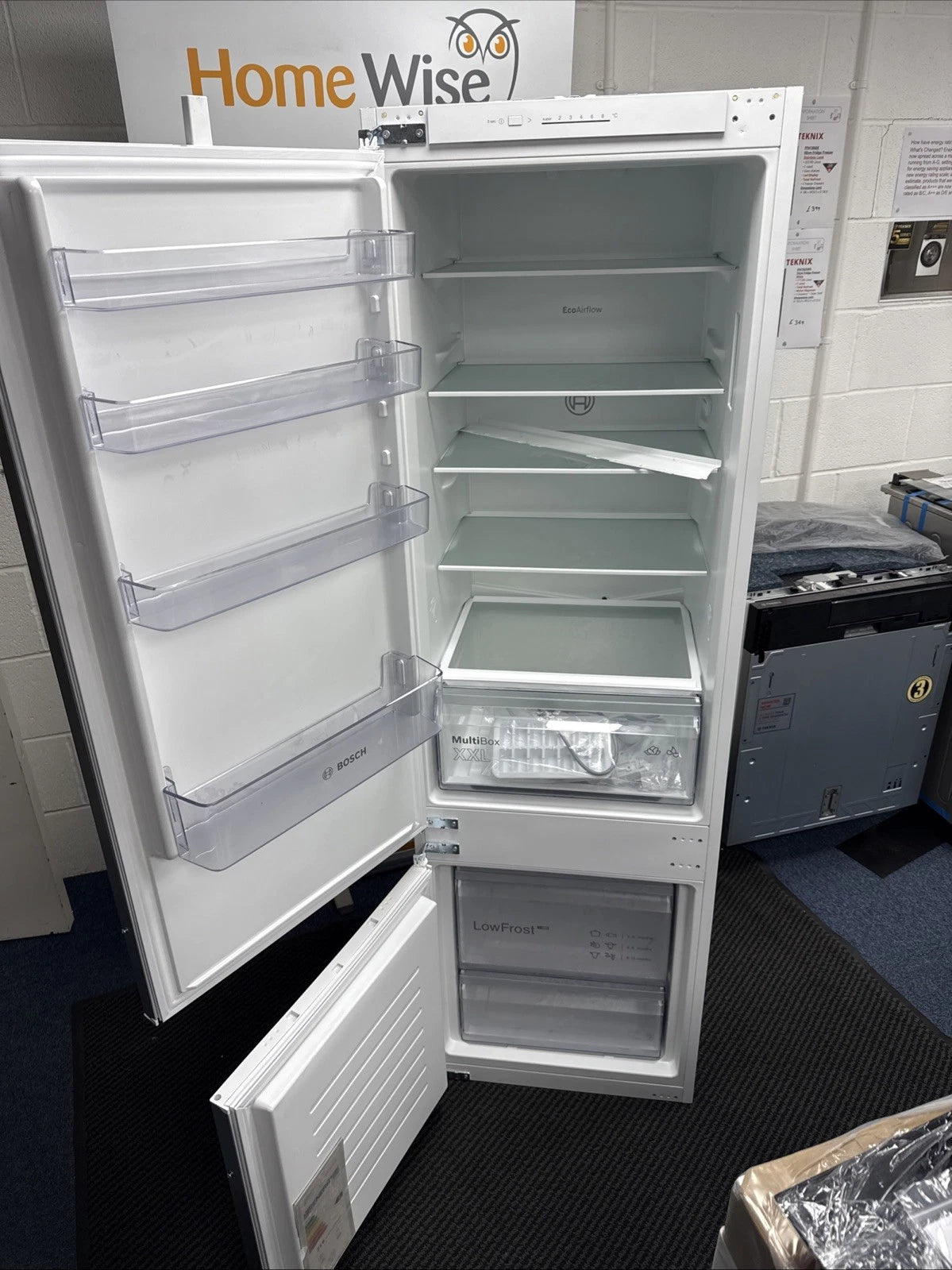 Bosch Series 2 KIV87NSE0G (09) 270 Litre 70/30 Integrated Fridge Freezer - E Rated from HomeWise Appliances. shop photo with doors open showing the interior.